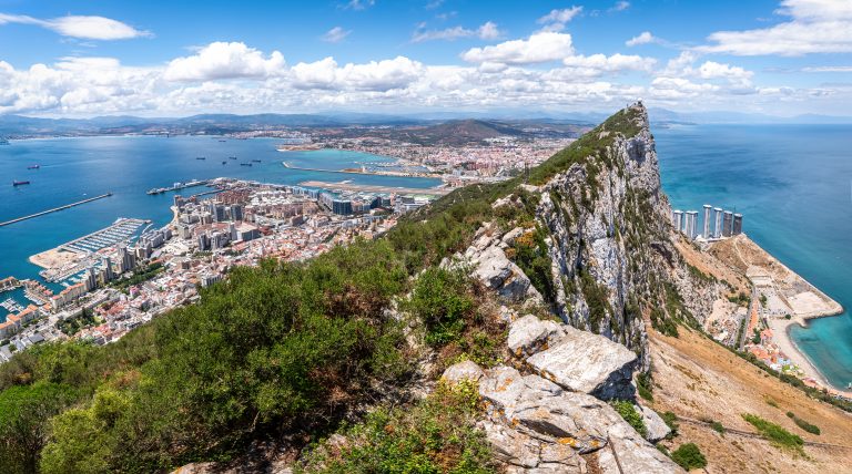 breathtaking-panoramic-view-of-gibraltar-featuring-the-iconic-rock-bustling-city-harbor-filled-with-ships-airport-and-stunning-coastline-under-blue-skies-and-white-clouds
